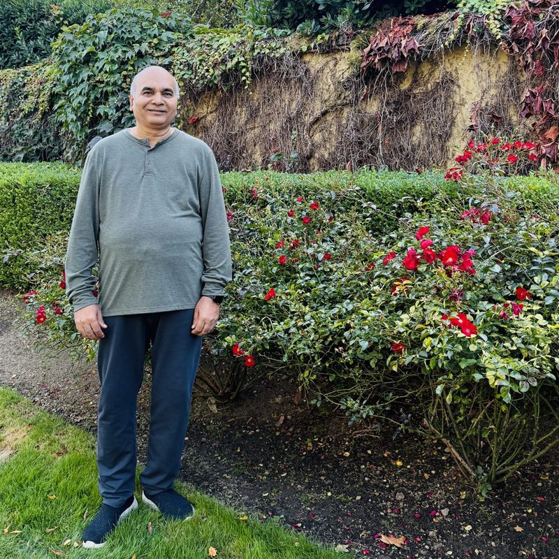 Dr. Dwivedi standing on a lawn beside a bed of red roses