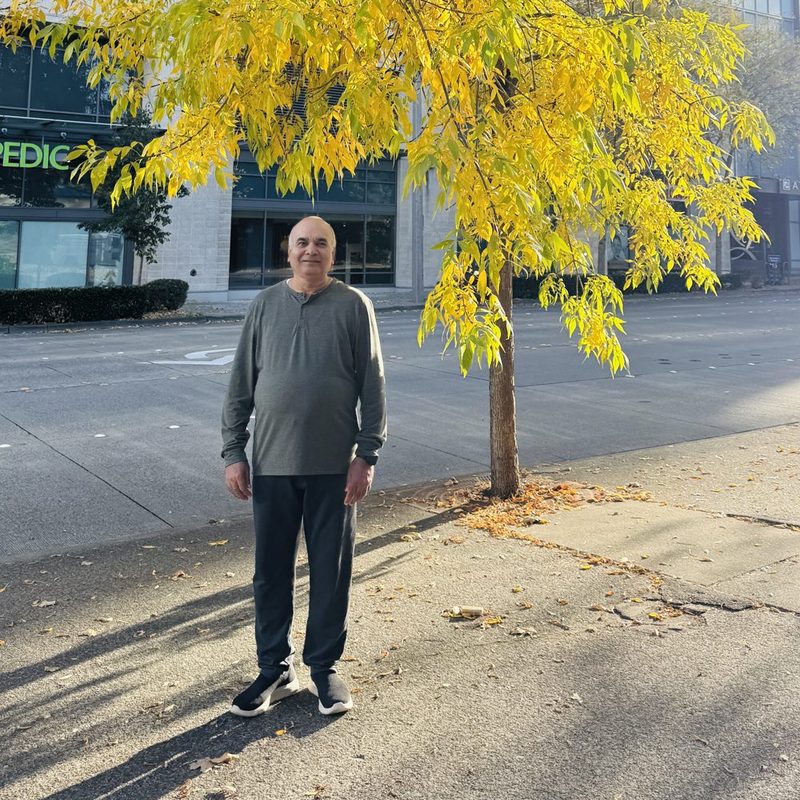 Dr. Dwivedi standing beneath a tree in bright yellow autumn leaf
